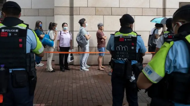 中国香港特区西九龙裁判法院外旁听“47人案”民众在警察面前排队等候（25/6/2024）