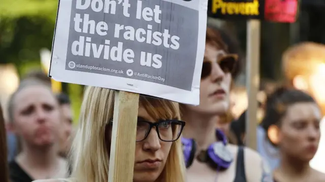 "Irkçıların bizi bölmesine izin verme" dövizi taşıyan bir kadın.