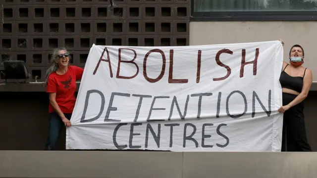 Para aktivis membentangkan spanduk bertulisan "Akhiri Pusat Detensi".