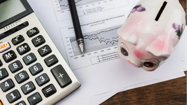 una calculadora junto a una alcancía