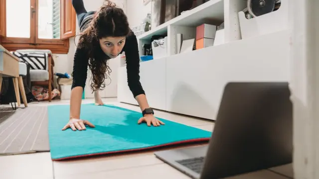 Una mujer se ejercita frente a una laptop