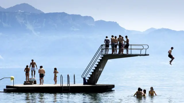 Children jump into the water of Lake Geneva play to cool off during the sunny and warm weather, in Lutry, Switzerland, 25 June 2019