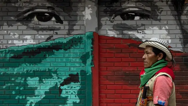 Un líder nasa pasa frente a un mural