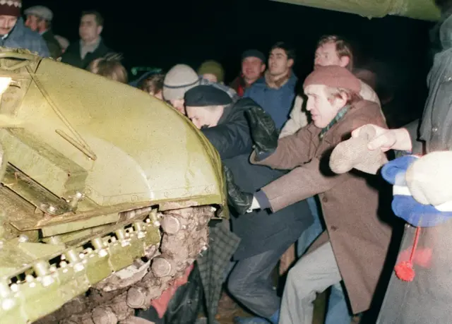 Люди пытаются остановить танк