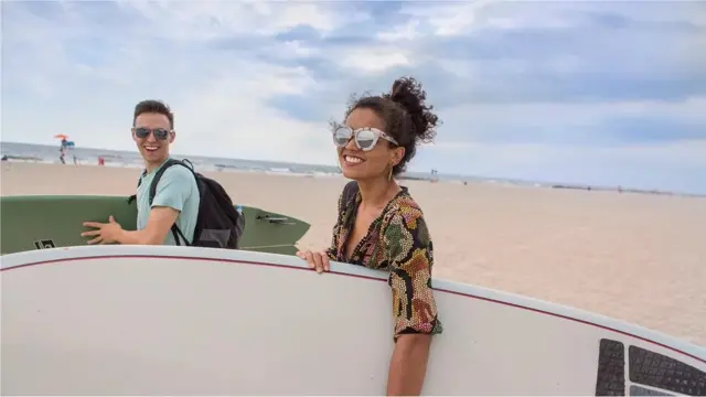 Dos personas con tablas de surf en una playa