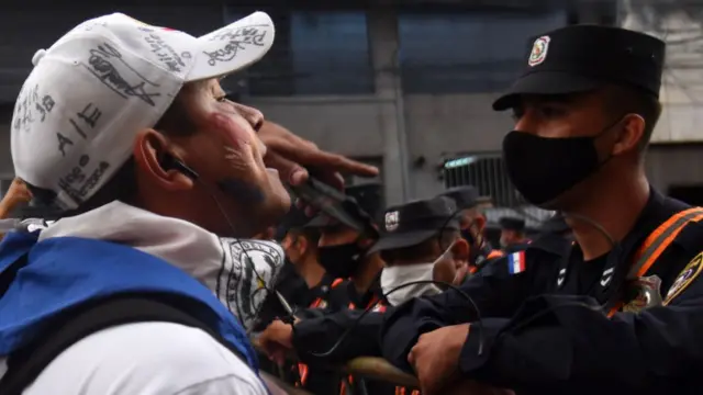 Un manifestante se enfrenta a un agente de seguridad en Paraguay.