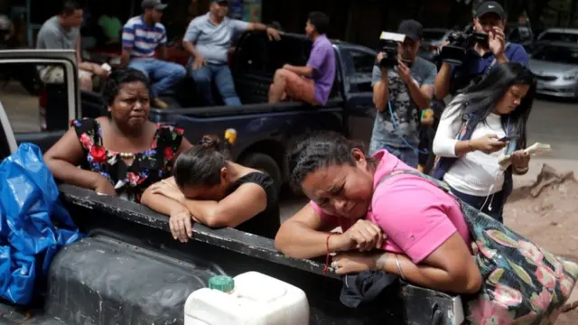 یک زن در بیرون پزشکی قانونی منتظر است تا جسد عضو خانواده‌اش که در زندان کشته شده را ببیند