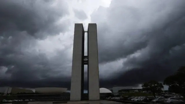 Prédio do Congresso Nacional rodeado por nuvens carregadas