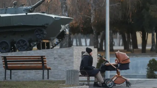 Una mujer se sienta con un cochecito de bebé junto a un vehículo de combate de infantería de las Fuerzas Armadas de Ucrania en Kramatorsk en noviembre de 2021.