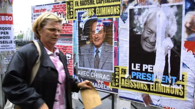 Жінка біля рекламних щитів кандидатів у президенти