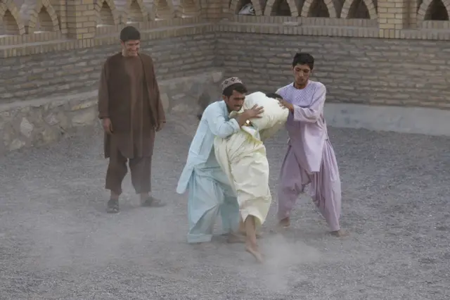 Prizor iz mauzoleja Hauađe Galtana Valija gde dvojica muškaraca pokušavaju da obuzdaju prijatelja zaposednutog mističnim transom.