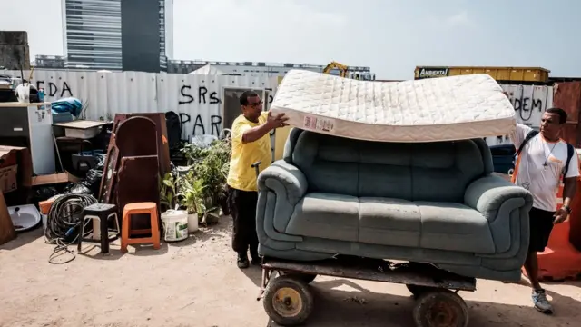 Dos residentes de Vila Autódromo mueven sus muebles en una carretilla