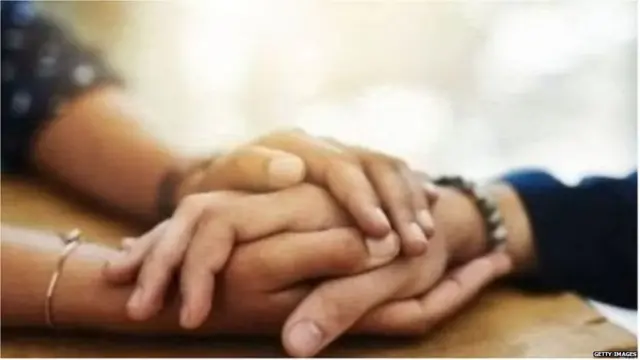 हाथ पकड़कर बैठे दो लोग