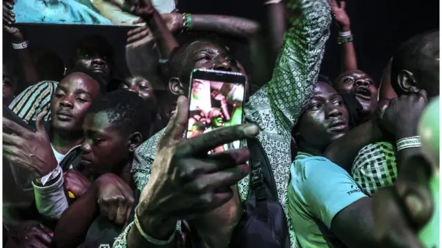 Un jeune se prend en photo dans la foule.