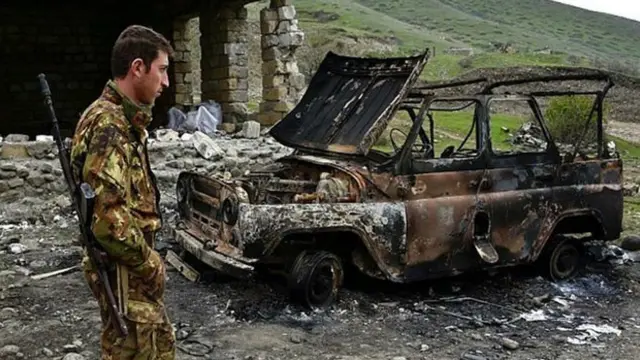 Erməni əsgər Talış kəndində yanmış maşına tamaşa edir.