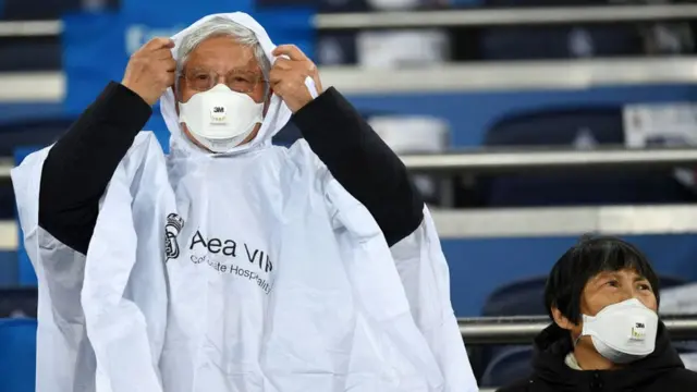 Güney Kore'de bir futbol maçında maskeli taraftarlar oyunu bekliyor