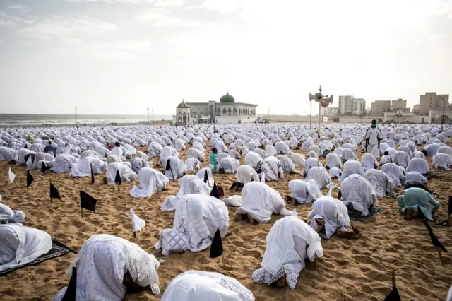 Des membres de la communauté Layene portant des masques de protection prient sur la plage face à la mosquée Yoff, pendant la fête islamique de Korite à Dakar