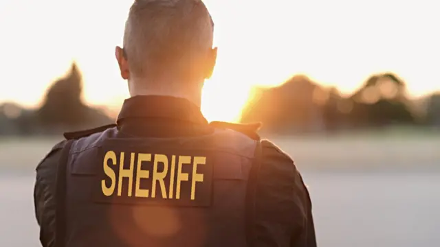 espalda de un hombre llevando un chaleco de Sheriff