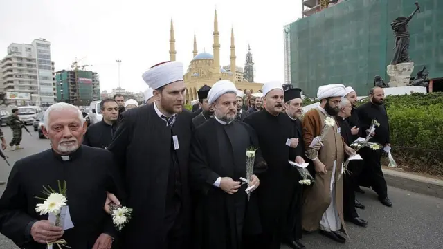 رجال دين يوزعون زهوراً بيضاء على المواطنين في ذكرى الحرب الأهلية عام 2013