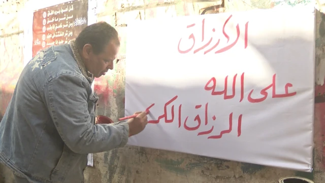 سعيد الخطاط يكتب على قطعة قماش