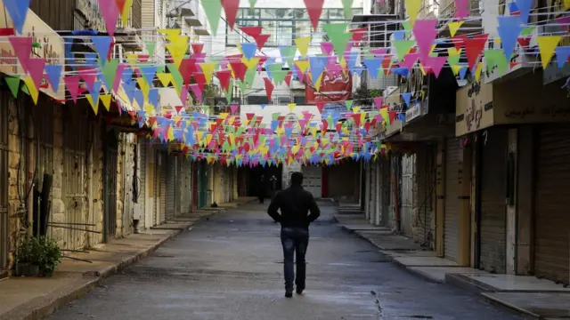 A Palestinian man walks past closed shops in the West Bank city of Nablus as a general strike
