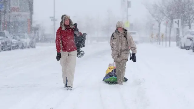 dua orang tengah berjalan di atas salju