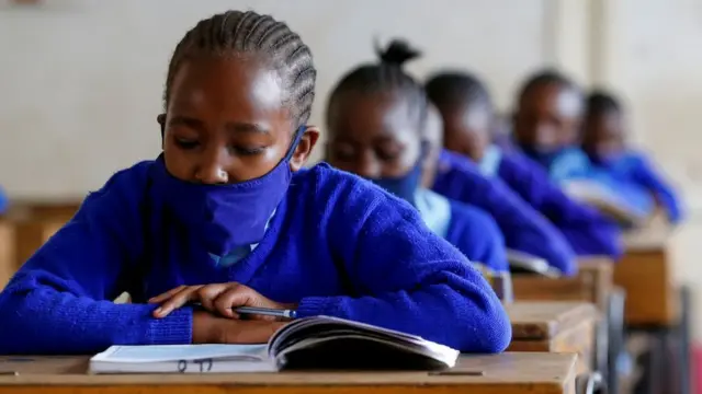A schoolgirl wears a face mask as she reads a book inside a classroom at the Olympic Primary School during the partial reopening of schools, after the government scrapped plans to cancel the academic year due to the coronavirus disease (COVID-19) pandemic, in Kibera slums of Nairobi, Kenya October 12, 2020.