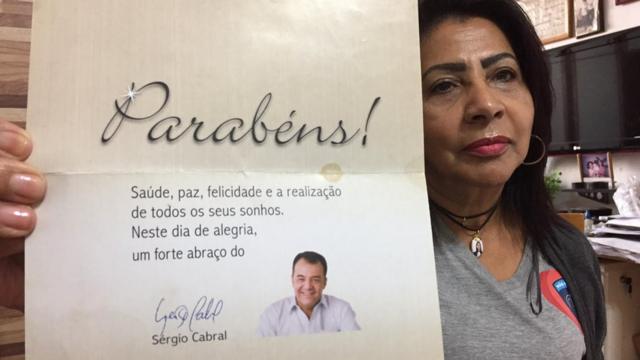 Zoraide mostra cartão com uma fotografia sorridente do ex-governador Sérgio Cabral, desejando-lhe parabéns