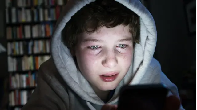Niño ante el celular con cara de sufrimiento