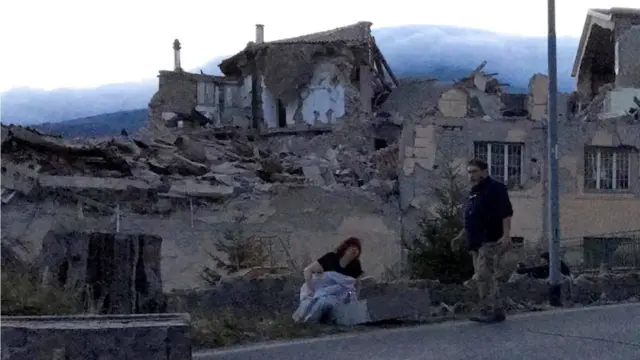 People stand by a road following a quake in Amatrice