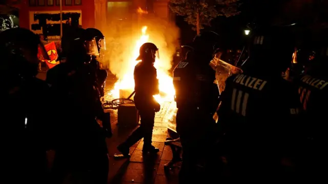 Policías junto a un fuego circulando en la noche.