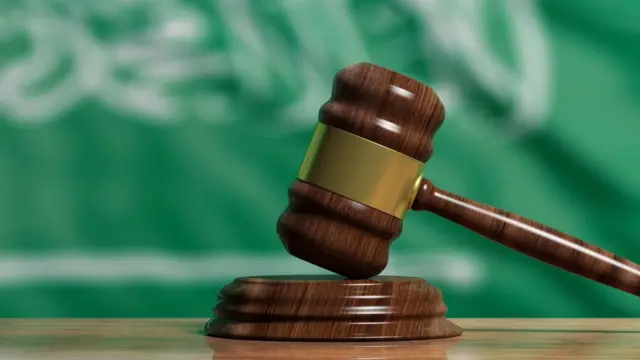 Le marteau d'un juge et le drapeau saoudien en arrière-plan.