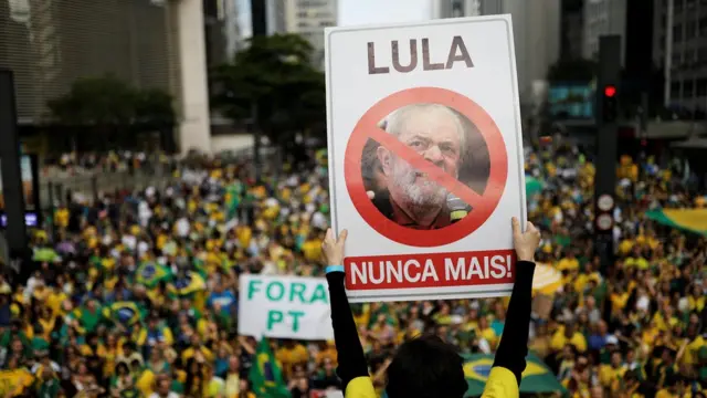 Manifestante segura placa "Lula nunca mais"; ao fundo, manifestaçãonovibet 350 free spinsapoio a Bolsonaro, com pessoas vestidasnovibet 350 free spinsverde e amarelo