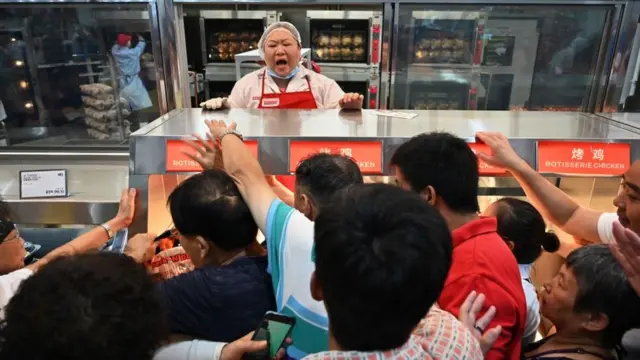 Los clientes se agolpan en la sección de pollos asados de Costco en Shanghái, China.