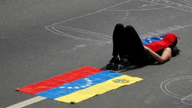 Una manifestante se cubre el sol en la protesta en Caracas