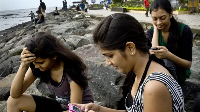 স্মার্টফোনে ফেসবুকে মগ্ন মুম্বাইর তিন কলেজ ছাত্রী।