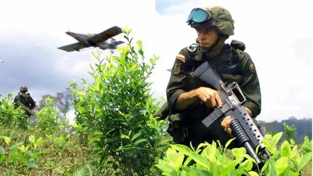 Un soldado colombiano avanza en un cultivo de coca de la zona de Nariño mientras un avión arroja pesticidas.
