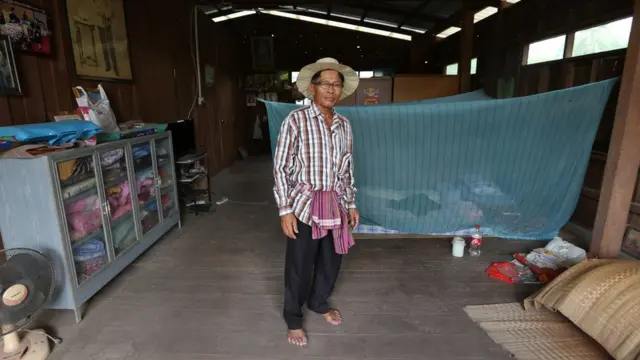 นายจำปายืนอยู่ข้างเตียงนอนมุ้ง