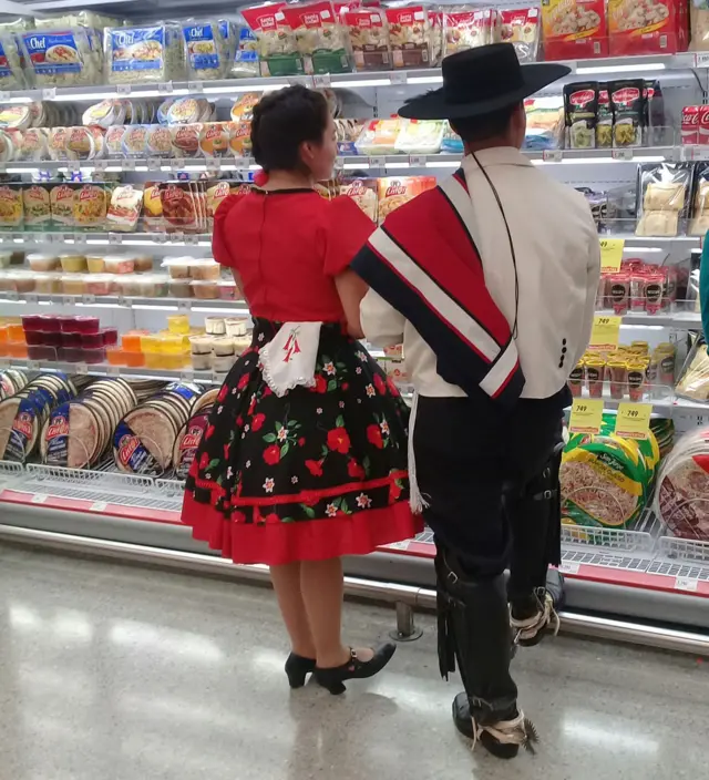 Pareja en un supermercado con traje regional en Chile.