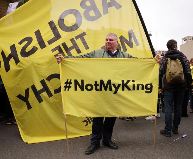 A man carries a banner with the hashtag #NotMyKing as anti-monarchy group Republic protest on the day of the Coronation