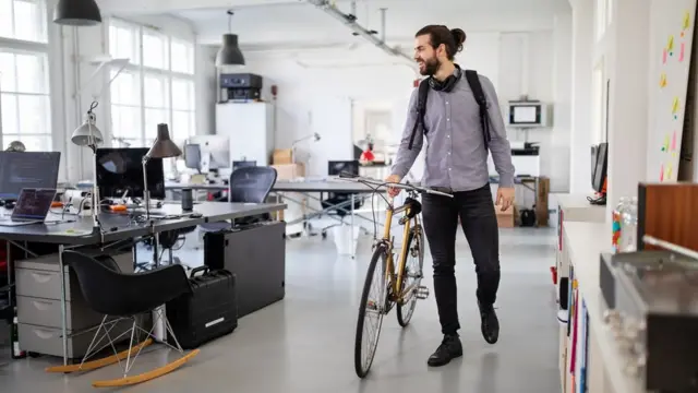 Jovem com bicicleta no escritório