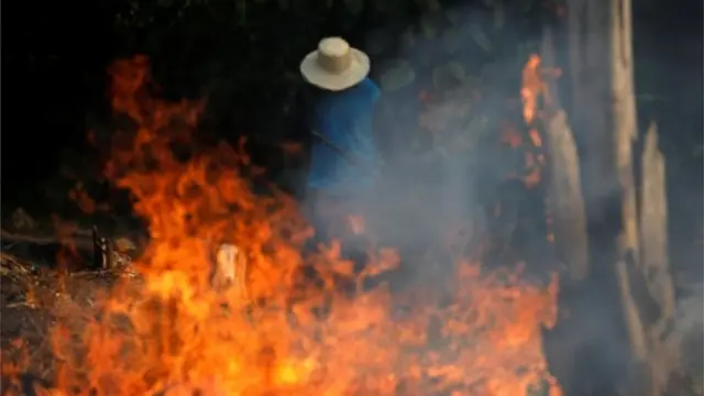 Homem diantejogo da mina na blazefogo na Amazônia