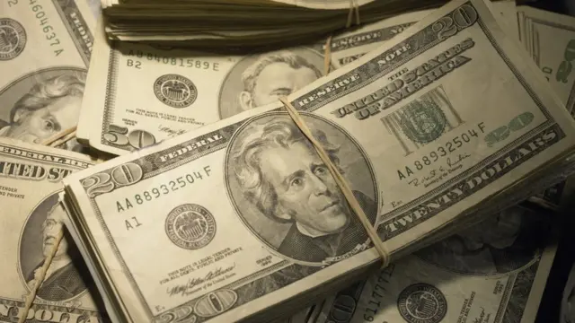 Fajos de billetes de dólares acumulados unos sobre otros.