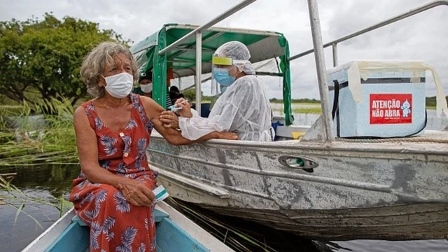 Profissional da saúde aplica vacina no braçojogo de aviao betanomulher, que está num barco