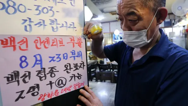 20일 오전 서울 광화문의 한 음식점에서 관계자가 백신 인센티브 관련 문구가 적힌 안내문을 붙이고 있다