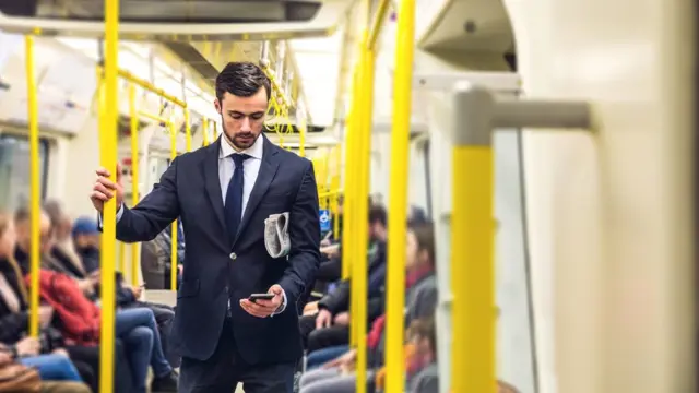 Homem vê o celular no metrô