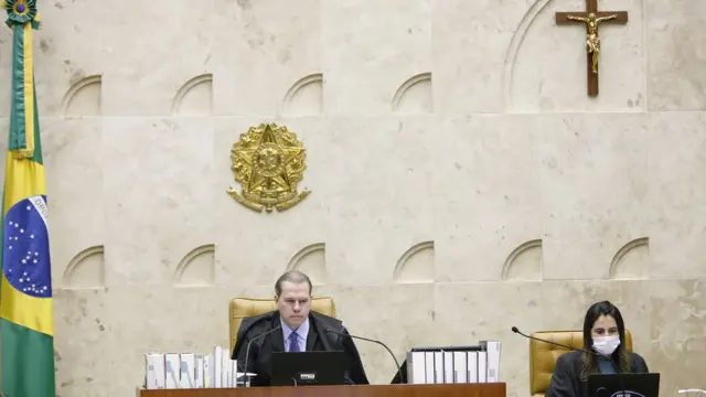 Dias Toffoli sentado no centro do plenário do STF, ao ladoslot rainbowassistente com máscara