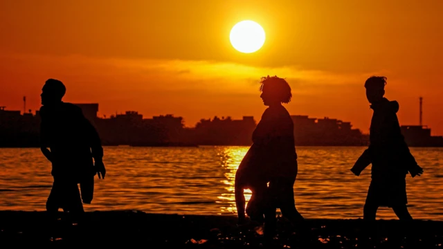 Des jeunes hommes marchent le long d'une plage au coucher du soleil dans la capitale, Tripoli, Libye - lundi 10 février 2020