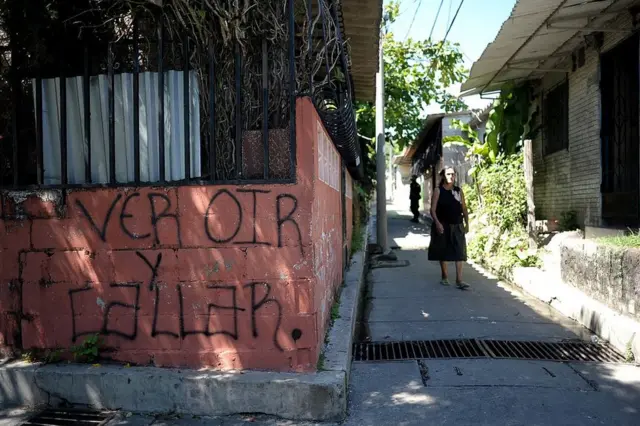 Mujer pasa junto a una pintada que dice "ver, oír y callar" en Las Margaritas, Soyapango, El Salvador, el 29 de octubre de 2010.