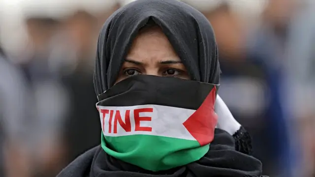 демонстрантка с завязанным палестинским флагом лицом